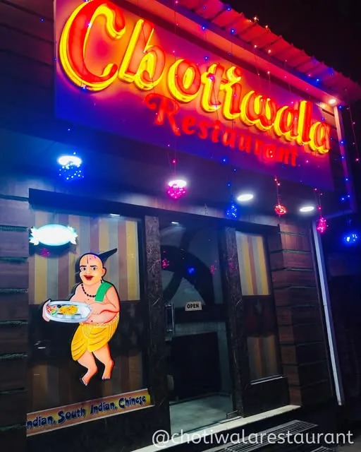 The red Chotiwala Restaurant signboard lit up at night